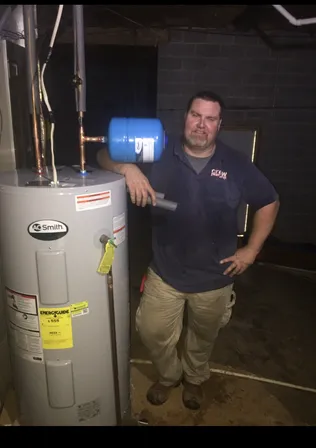 Crew Plumbing team member next to a newly installed water heater